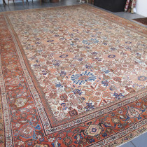 Fereghan Carpet - Large Fereghan carpets of any colour and design are becoming increasingly hard to source. Dark blue Herati design examples do appear on occasion. So I was delighted to find this beauty recently in the English countryside.The repeating design of stylised fans and floral ornaments is delightful, and is enhanced by ivory background in the field and delicate range of secondary colours. Note the gorgeous terracotta main border with the classic Fereghan design of palmettes, blossoms and meandering vines. This is an attractive and decorative country house style carpet in an excellent size. The overall condition is good. The ends and sides are intact, and the selvages are original. The pile is generally good throughout with areas of minor wear in places. If you are looking for a decorative antique carpet, this rare beauty is a great choice, and would enhance any number of settings. Image of Fereghan Carpet